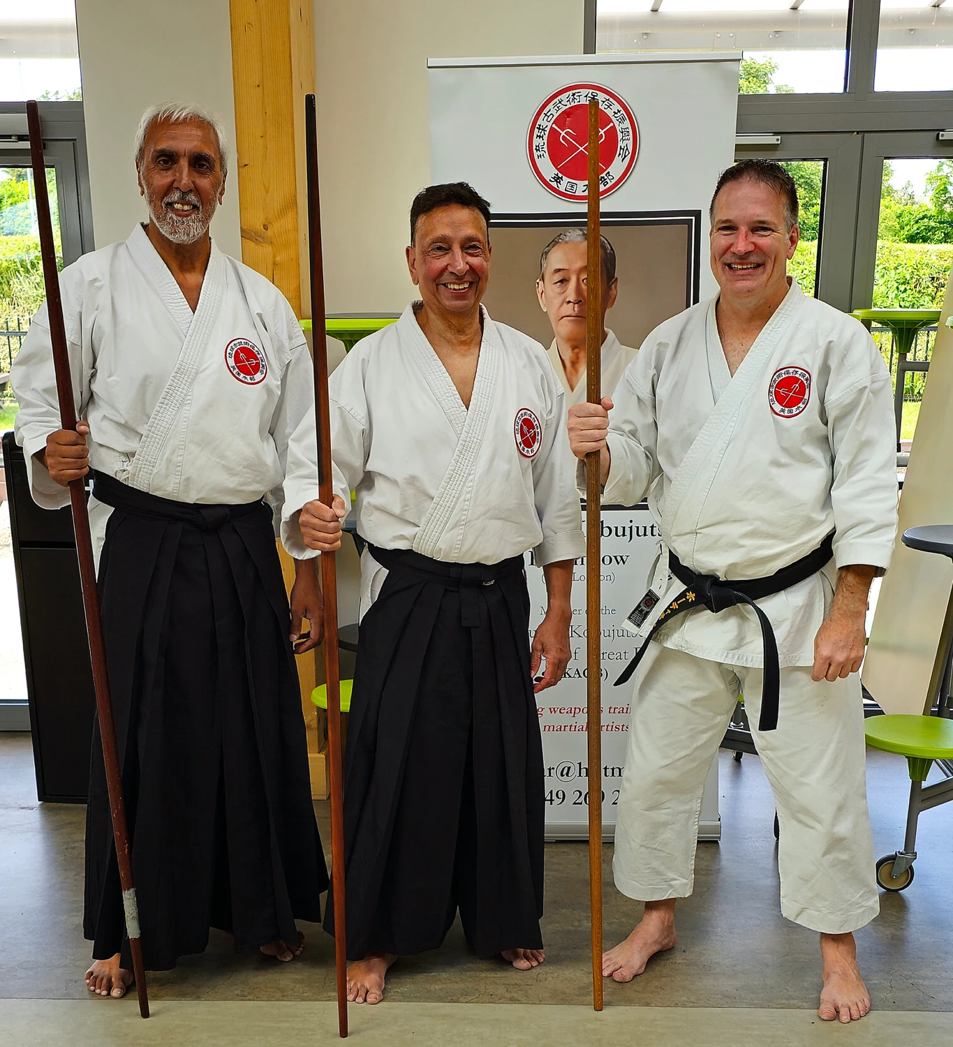 Three martial artists standing together with Bo